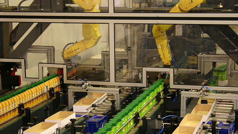 Lineas automatizadas de pick and place con brazos robóticos antropomórficos que colocan los botes en el packaging final.